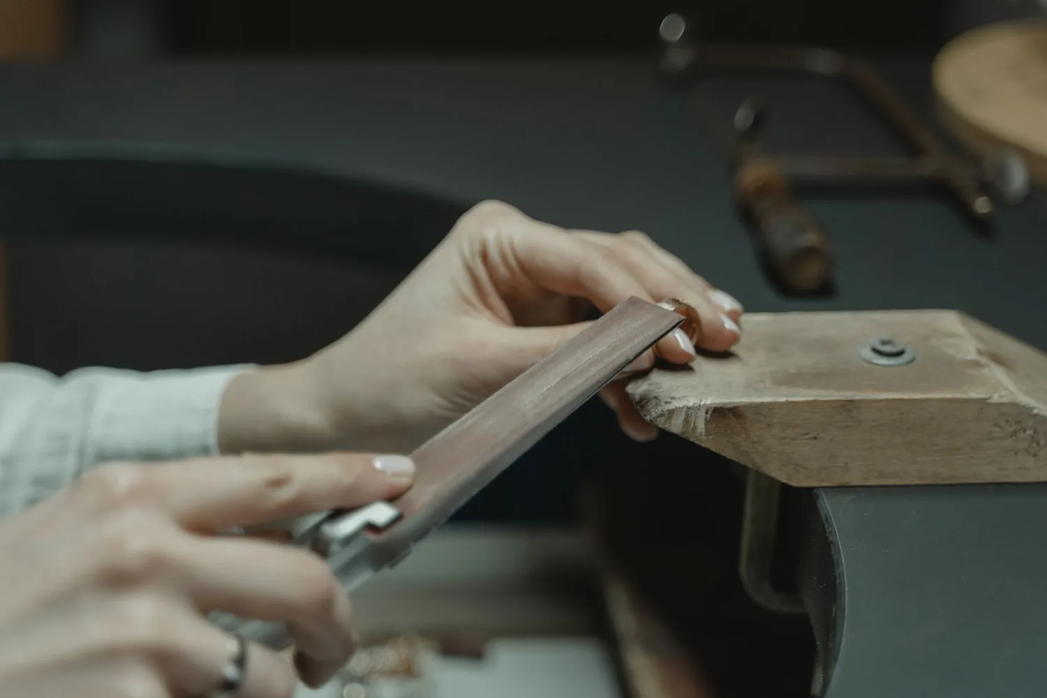 A jeweler's hands working at a bench